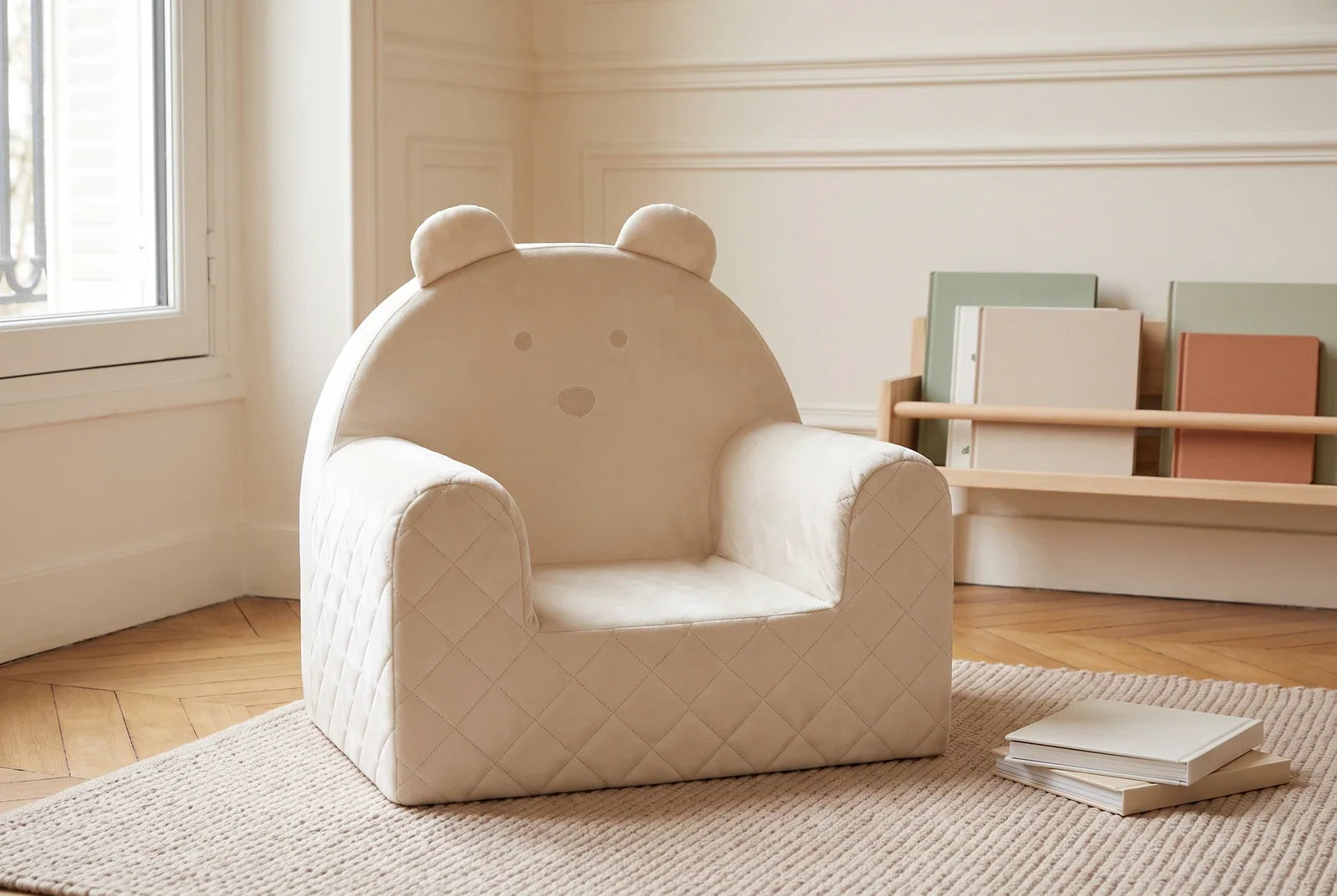 Fauteuil bébé ourson en velours beige dans un coin lecture lumineux, avec une étagère à livres et un tapis