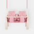 Balançoire double jumeaux en velours rose, vue de face : double siège, barre en bois et pompons
