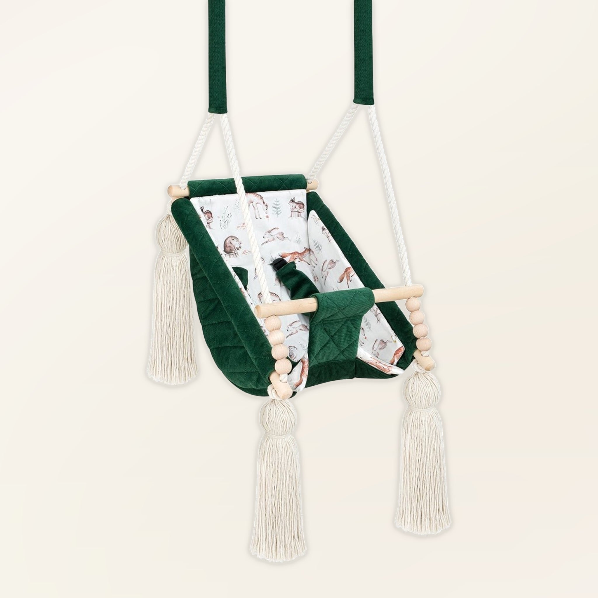 Hamac bébé suspendu en velours vert, vue de trois quarts : pompons, perles en bois et assise rembourrée