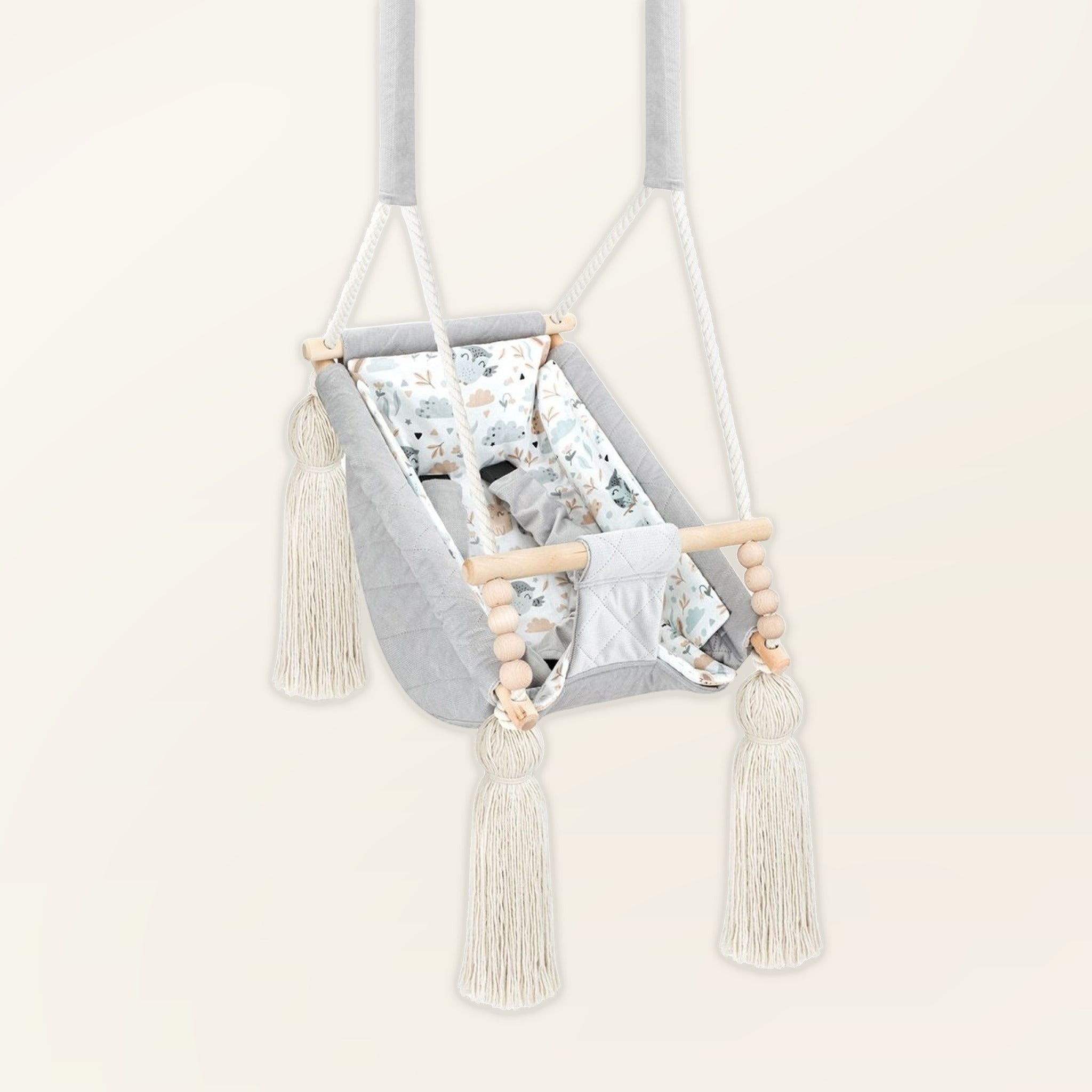 Hamac bébé suspendu en velours gris clair, vue de trois quarts : pompons, perles en bois et assise rembourrée