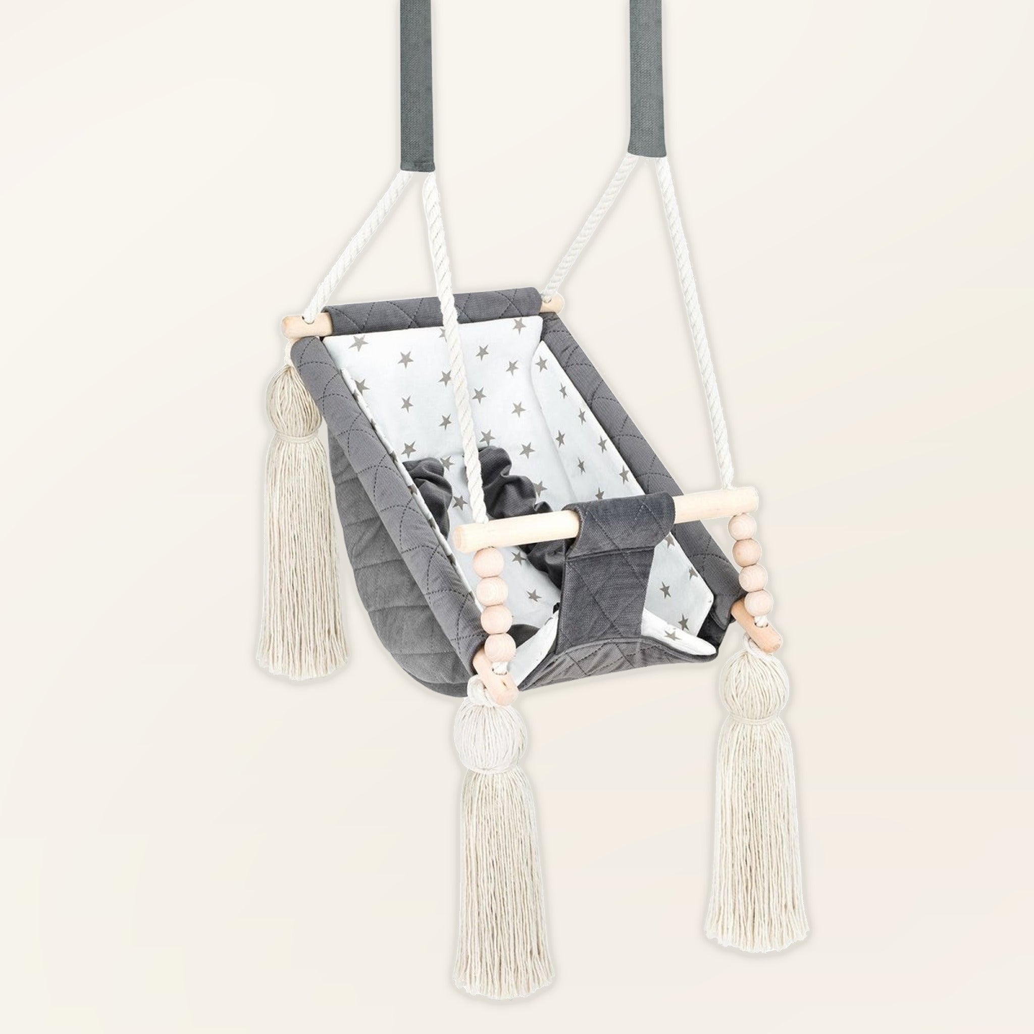Hamac bébé suspendu en velours gris foncé, vue de trois quarts : pompons, perles en bois et assise rembourrée