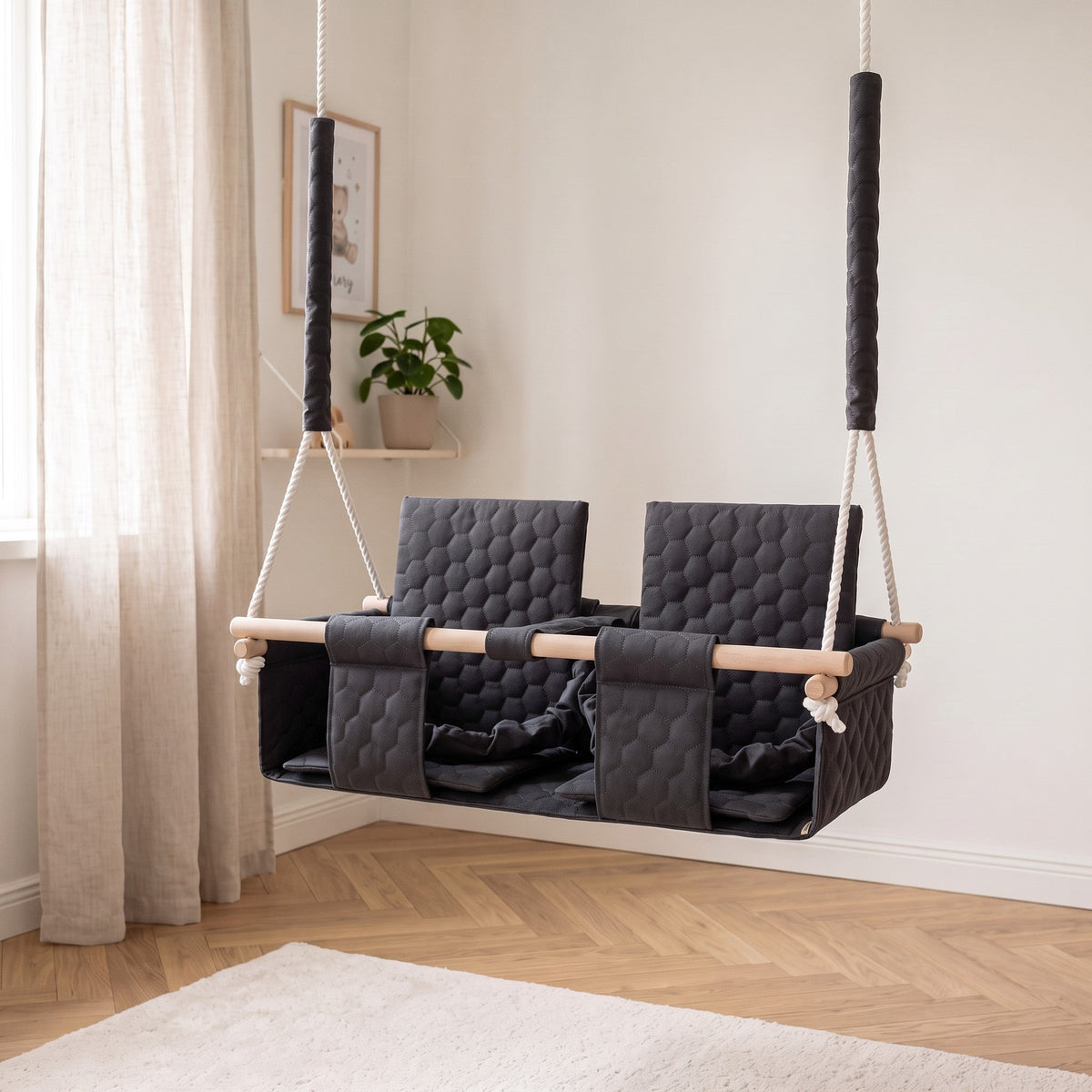 Balançoire double jumeaux imperméable gris foncé, dans une chambre d'enfant lumineuse de style scandinave