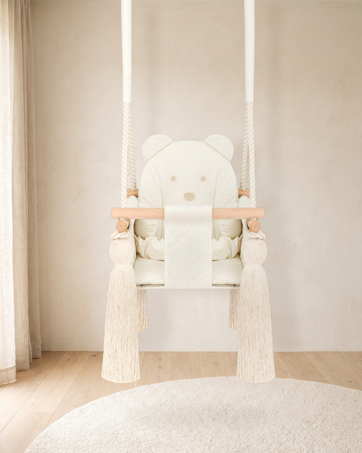 Balançoire bébé en velours beige avec dossier ourson, suspendue dans une chambre d'enfant lumineuse