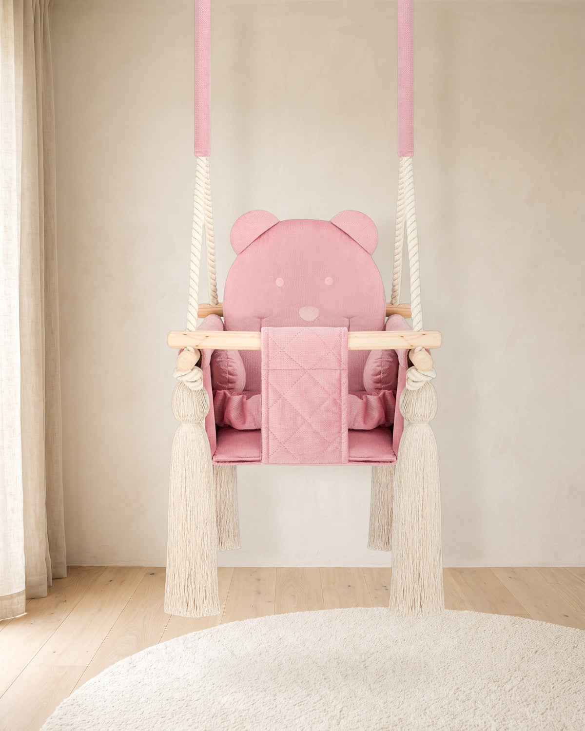Balançoire bébé en velours rose avec dossier ourson, suspendue dans une chambre d'enfant