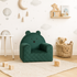 Fauteuil bébé ourson en velours vert, dans une chambre d'enfant avec jouets et étagère
